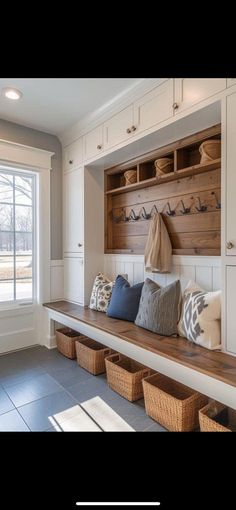 a wooden bench sitting next to a window in a room with white cabinets and drawers