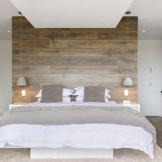 a large white bed sitting in a bedroom next to a wooden wall