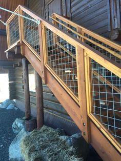 a wooden staircase with metal railings and bales on the bottom floor next to a log cabin