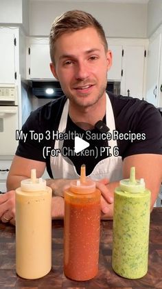 a man sitting at a kitchen counter with three condiments in front of him