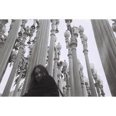 a woman standing in front of many tall poles