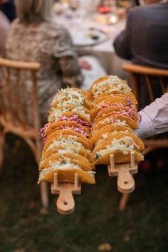 people sitting at a table with food on wooden sticks