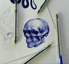 a drawing of a skull and two birds on top of paper next to pencils