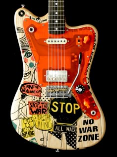 an electric guitar with various stickers on it's body and neck, sitting in front of a black background