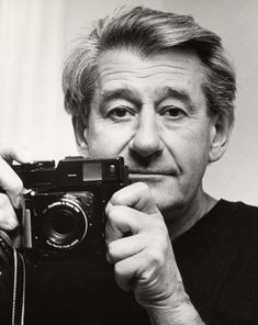 black and white photograph of man holding up camera