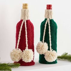 two knitted wine bottles with pom - poms hanging from the top and bottom