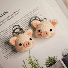 two crocheted pig key fobs are sitting on top of an open book