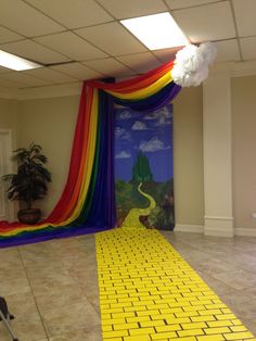 a room with a yellow brick floor and a rainbow colored drape on the wall