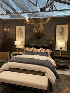 a bed room with a neatly made bed and a deer head mounted to the wall