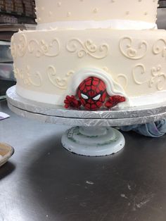 a white cake with spiderman decorations on it