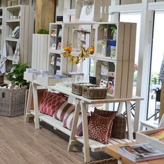 the inside of a store with lots of furniture and flowers in vases on shelves