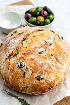 a loaf of bread sitting on top of a table next to bowls of olives