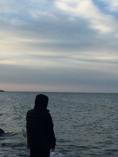 a person standing on the beach looking out at the water