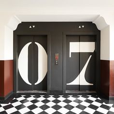 two black and white doors with the number seventy on them in front of a checkered floor