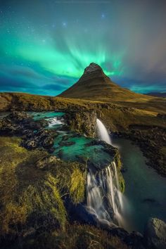 the aurora lights over a waterfall in iceland