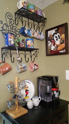 a coffee bar with mickey mouse mugs and other items on the wall above it