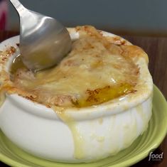 a person is dipping cheese into a dish on a green plate with a ladle