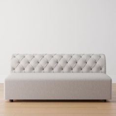 a couch sitting on top of a hard wood floor next to a white wall in an empty room