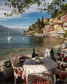 an outdoor dining area with tables and chairs overlooking the water