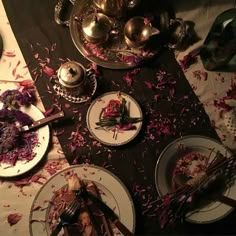 a table topped with plates and silverware covered in rose petals