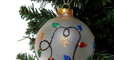 a glass ornament hanging from a christmas tree with beads and lights on it