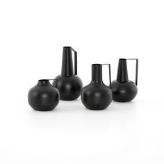 three black vases sitting next to each other on a white surface, one is empty