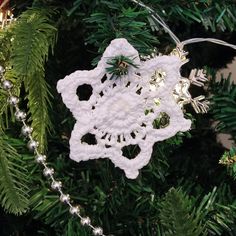 a crocheted snowflake ornament hanging from a christmas tree