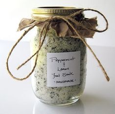 a jar filled with green and white stuff on top of a table next to a tag that says peppermint lemon foot scrub handmade