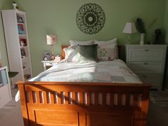 a bed room with a neatly made bed and green walls