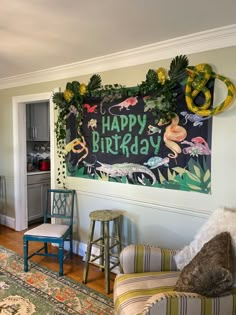 a happy birthday sign on the wall in a living room with chairs and rugs