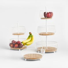 three tiered fruit baskets with bananas, apples and pears in them on white background