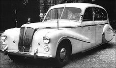 an old white car parked in front of a building