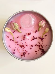 a bowl filled with liquid and flowers on top of a table