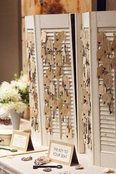 two white shutters with signs attached to them sitting on a table next to flowers