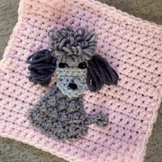 a crocheted square with a poodle on it, sitting on the ground