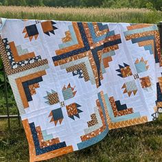 two quilts hanging on a clothes line in the grass