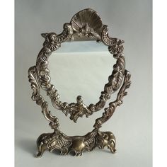 an ornate silver mirror sitting on top of a table