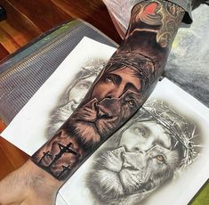 a man's arm with tattoos on it and an image of jesus, lion and cross