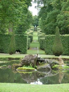 a pond in the middle of a lush green park