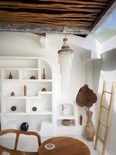 a living room with white walls and shelves filled with vases, bookshelves and other items