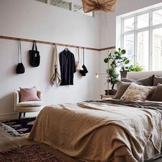 a bed sitting in a bedroom next to a wall mounted potted plant and hanging utensils