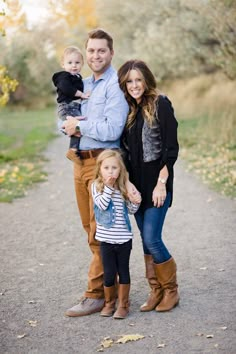 a man, woman and child posing for a photo on a path with trees in the background