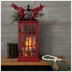 a red lantern sitting on top of a wooden table next to a book case and christmas decorations