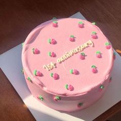 a pink cake sitting on top of a white plate with the word congratulations written on it