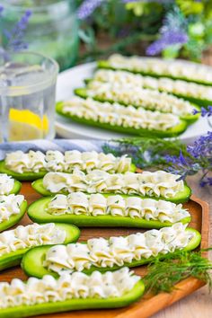 cucumber and cheese appetizers on a wooden platter with flowers in the background