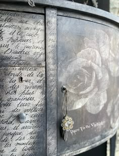 an old metal cabinet with writing on it and a rose hanging from the front door