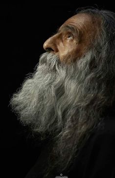 an old man with long grey hair and a beard is looking up at the sky