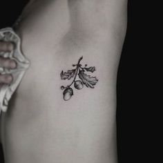 a woman's chest with leaves and acorns tattoo on her left side