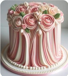 a pink and white striped cake with roses on it's top, sitting on a plate