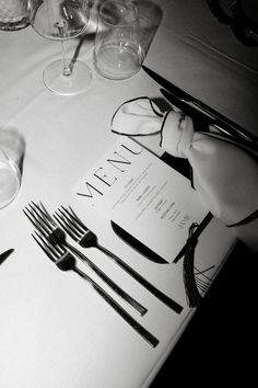 the table is set with silverware and wine glasses